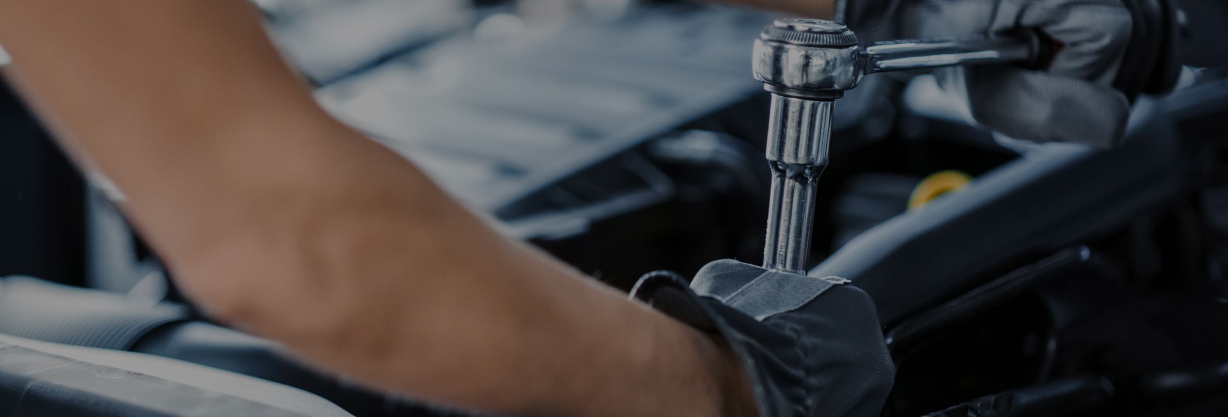 Nahaufnahme einer Person die an einem Automotor schraubt